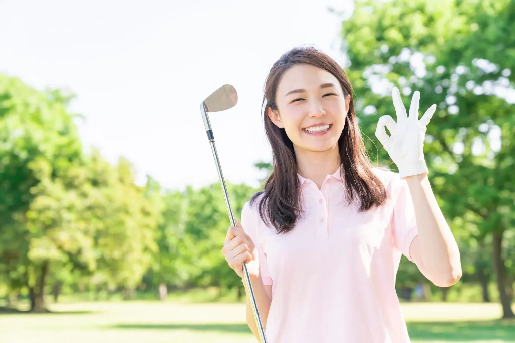 笑顔でゴルフクラブを持つ女性の写真
