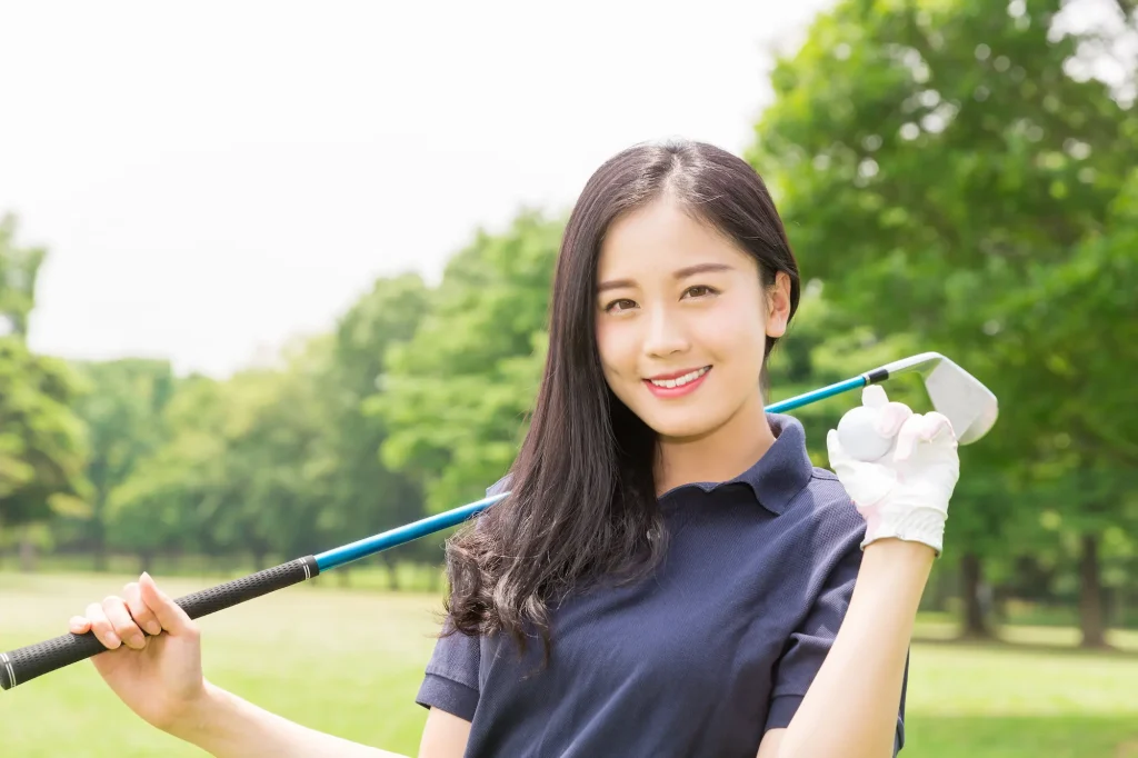笑顔でゴルフボールを持つ女性の写真